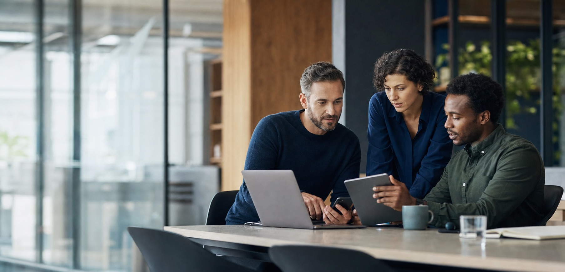 Ein Team stimmt seine digitale Kommunikation gemeinsam an Laptop, Tablet und Smartphone ab